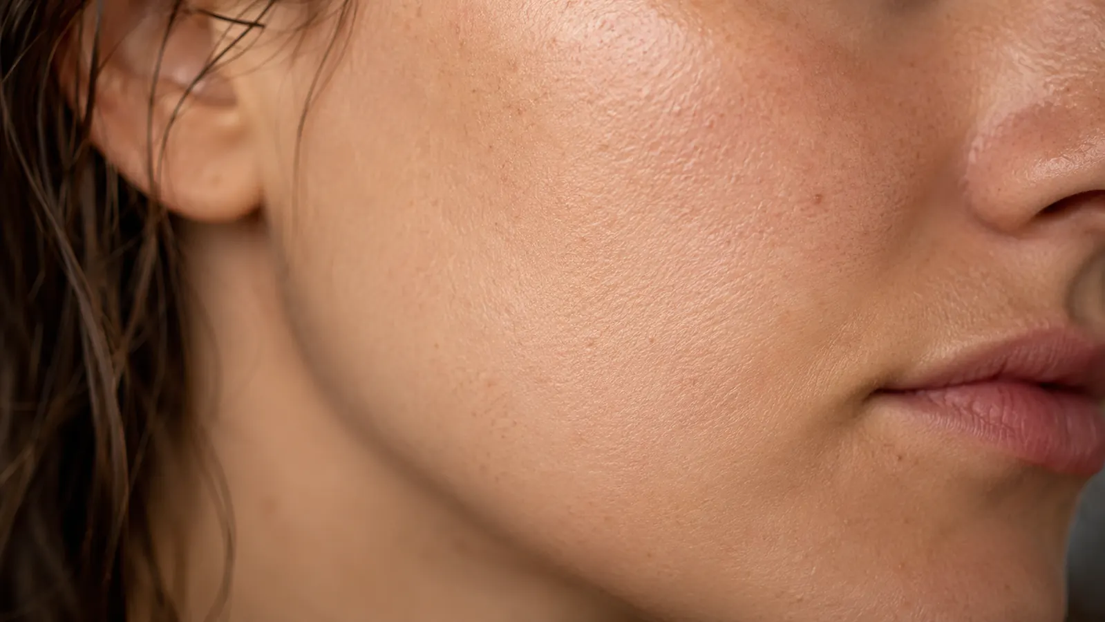 Close-up of smooth, hydrated skin on a woman's cheek and jawline in natural light