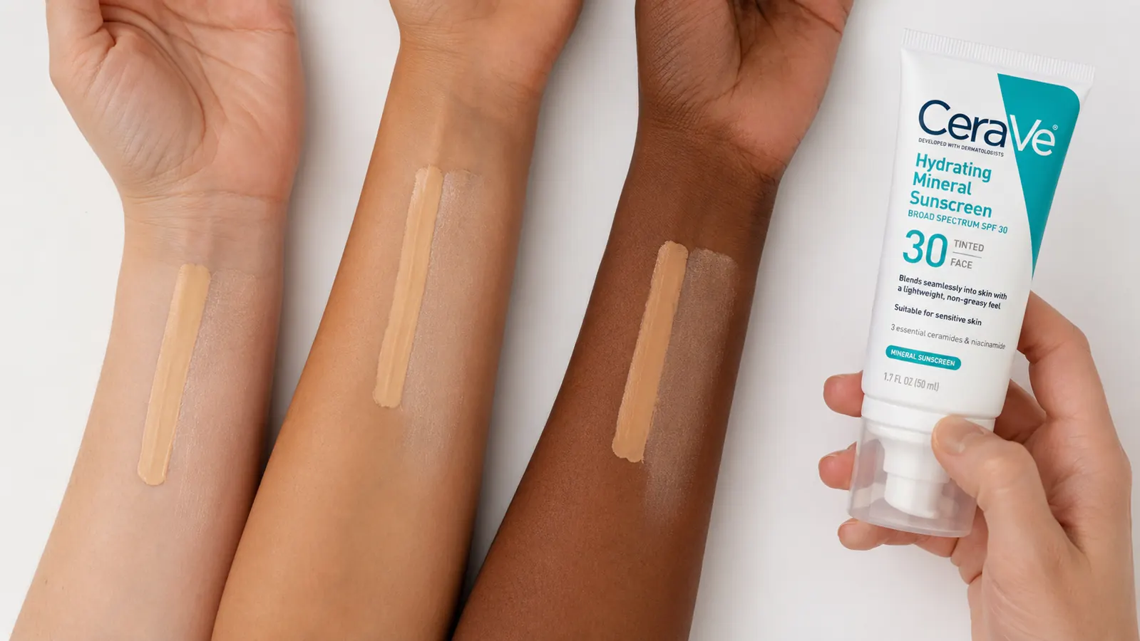 Close-up of tinted sunscreen swatched across four skin tone strips from fair to medium-deep, showing how the single beige shade looks on each