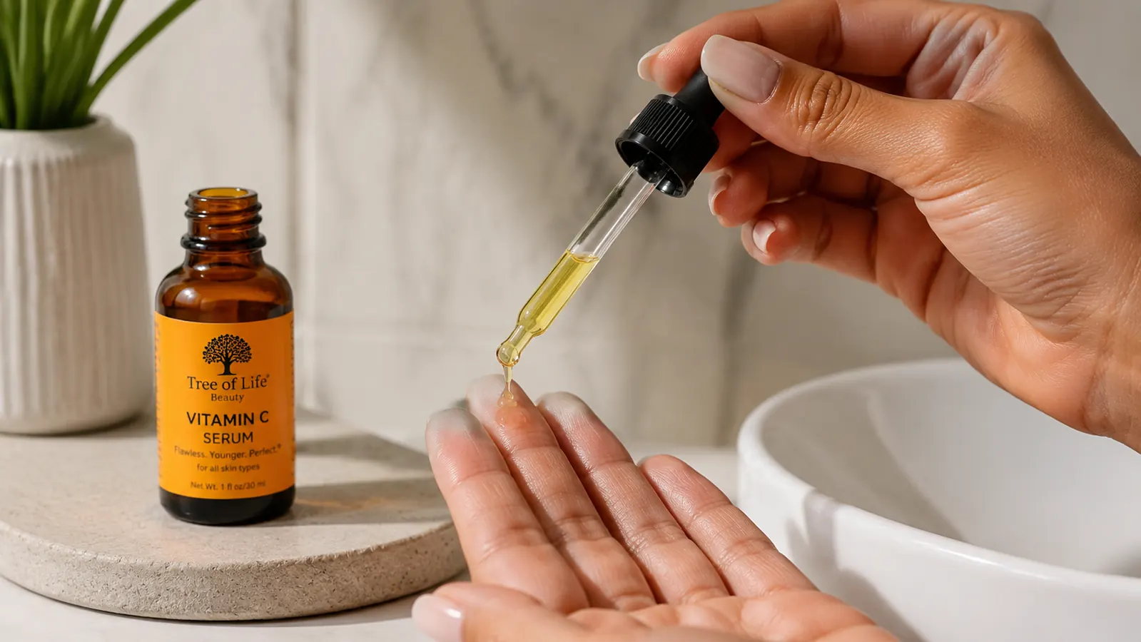 A hand pressing two drops of serum onto fingertips over a white bathroom sink